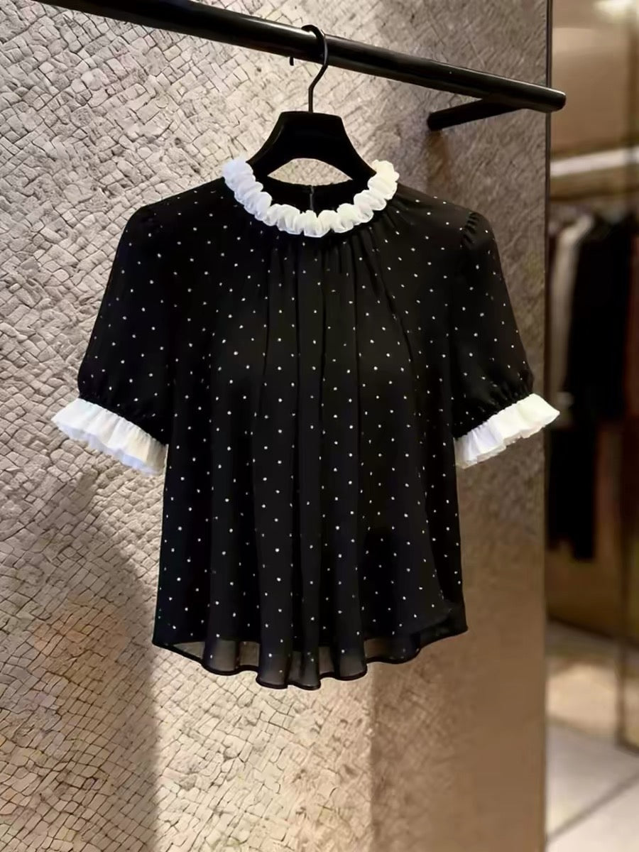 Women's black short-sleeved top featuring a stylish, unique design with a ruffled collar and polka-dot print; a chic, versatile, and flattering piece perfect for layering or wearing on its own in summer.