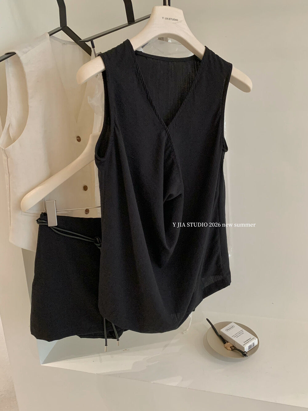 Elegant sleeveless draped-neck top with a high-waisted A-line skirt. Includes a belt and built-in safety shorts for a chic, polished look.