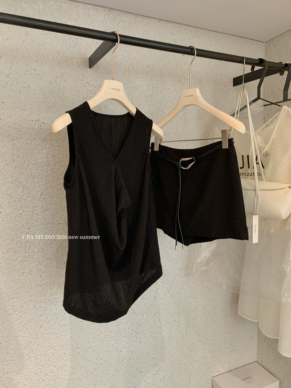 Elegant sleeveless draped-neck top with a high-waisted A-line skirt. Includes a belt and built-in safety shorts for a chic, polished look.