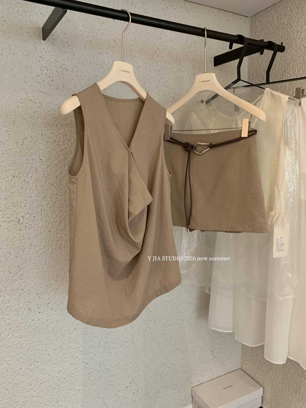 Elegant sleeveless draped-neck top with a high-waisted A-line skirt. Includes a belt and built-in safety shorts for a chic, polished look.