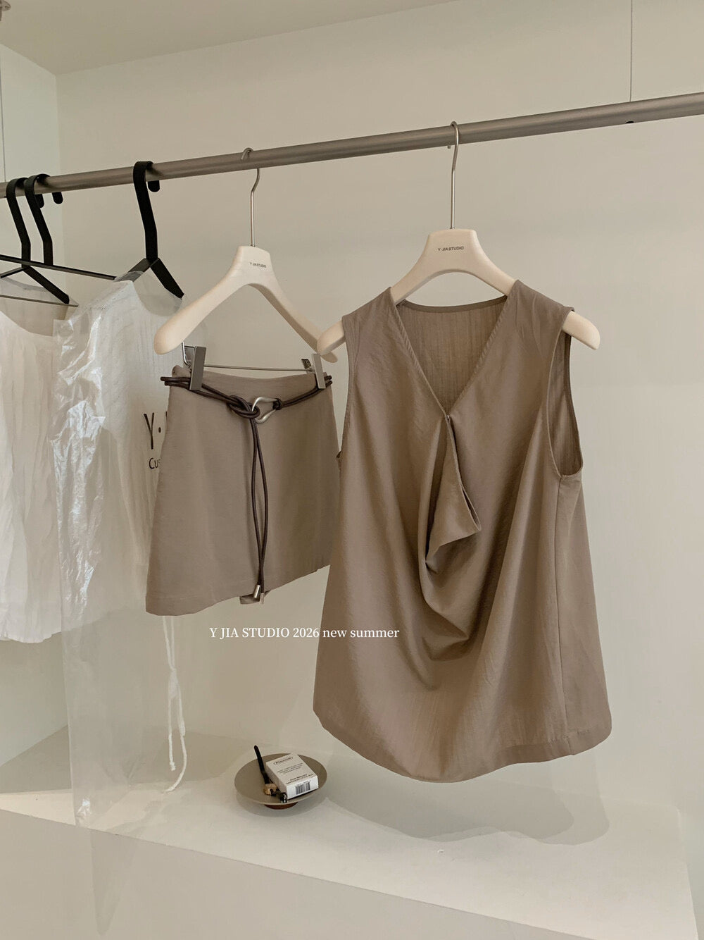 Elegant sleeveless draped-neck top with a high-waisted A-line skirt. Includes a belt and built-in safety shorts for a chic, polished look.