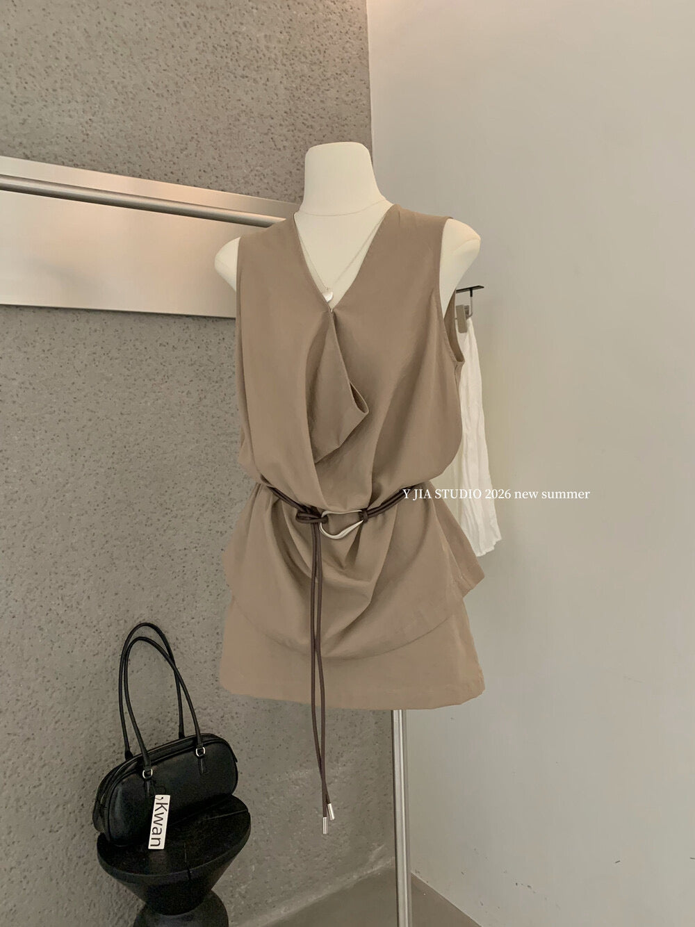 Elegant sleeveless draped-neck top with a high-waisted A-line skirt. Includes a belt and built-in safety shorts for a chic, polished look.