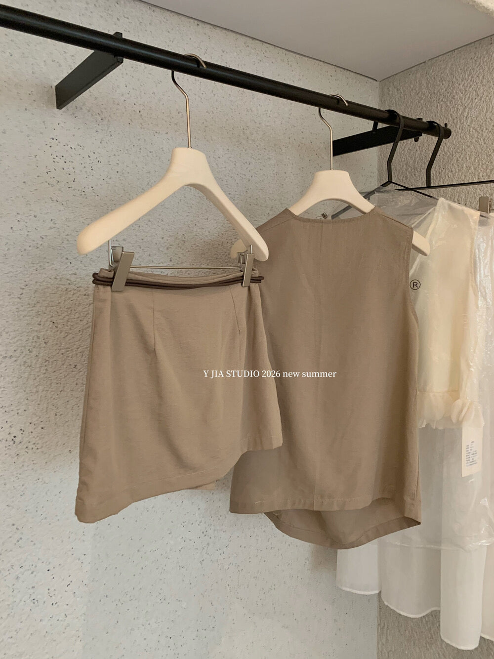 Elegant sleeveless draped-neck top with a high-waisted A-line skirt. Includes a belt and built-in safety shorts for a chic, polished look.