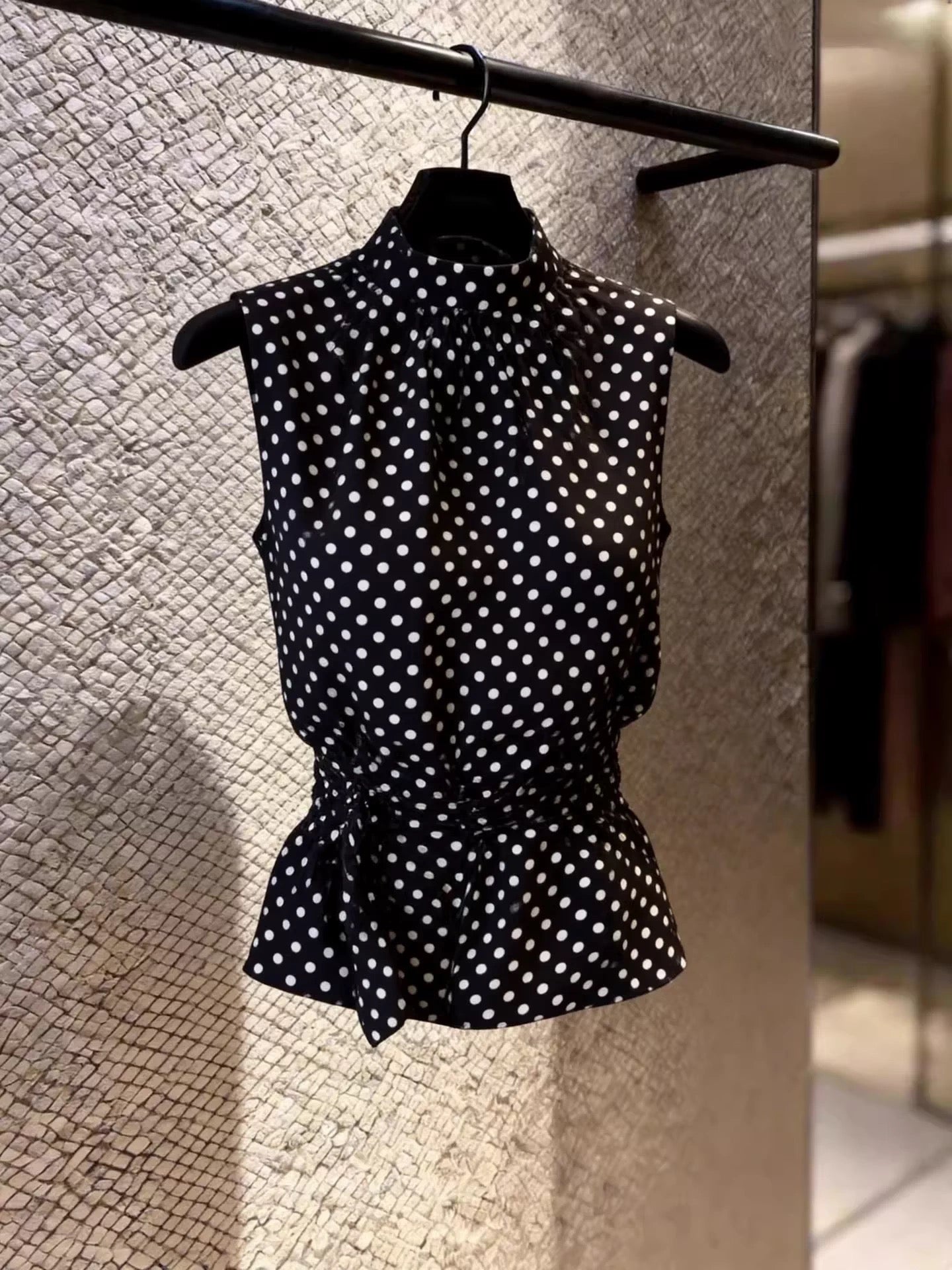 A stylish, French-style sleeveless black polka-dot blouse for women; features a waist-cinching design and a unique, chic aesthetic—sweet, stunning, and distinctive.