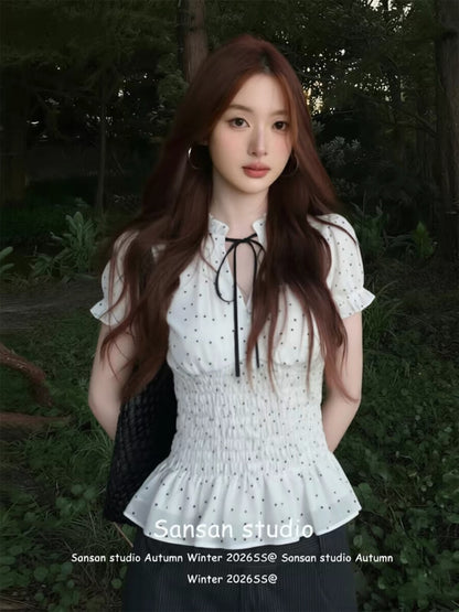 French-style white polka-dot short-sleeve blouse for women—perfect for early summer. Features puff sleeves, a waist-cinching fit for a slimming look, and lettuce-edge detailing.