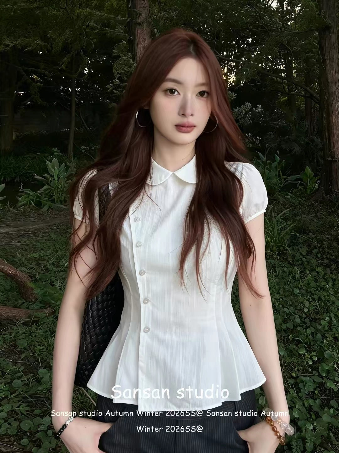 Women's white short-sleeve blouse featuring a Peter Pan collar, pleated detailing, and puff sleeves; a waist-cinching, slimming summer top.