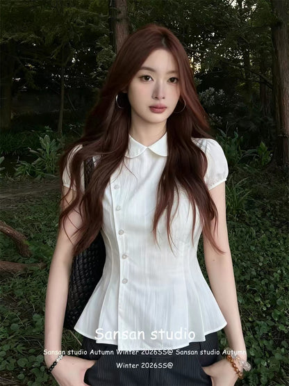 Women's white short-sleeve blouse featuring a Peter Pan collar, pleated detailing, and puff sleeves; a waist-cinching, slimming summer top.