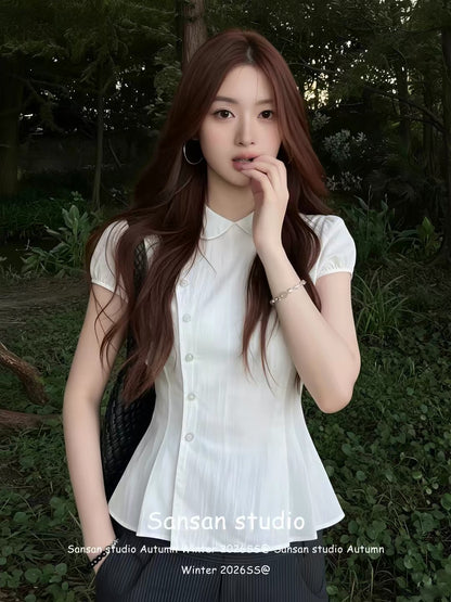 Women's white short-sleeve blouse featuring a Peter Pan collar, pleated detailing, and puff sleeves; a waist-cinching, slimming summer top.