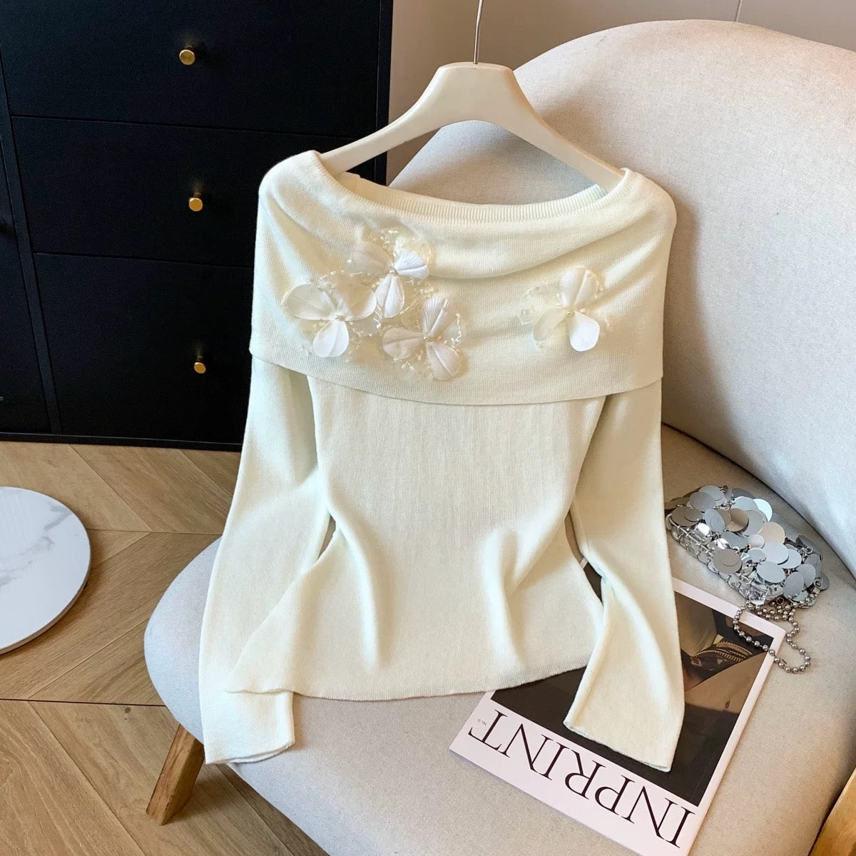 A must-have! This long-sleeved knit top with beaded 3D floral details is a sweet and spicy off-shoulder style perfect for autumn.