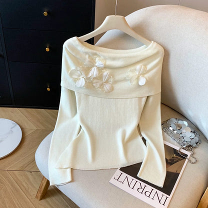 A must-have! This long-sleeved knit top with beaded 3D floral details is a sweet and spicy off-shoulder style perfect for autumn.