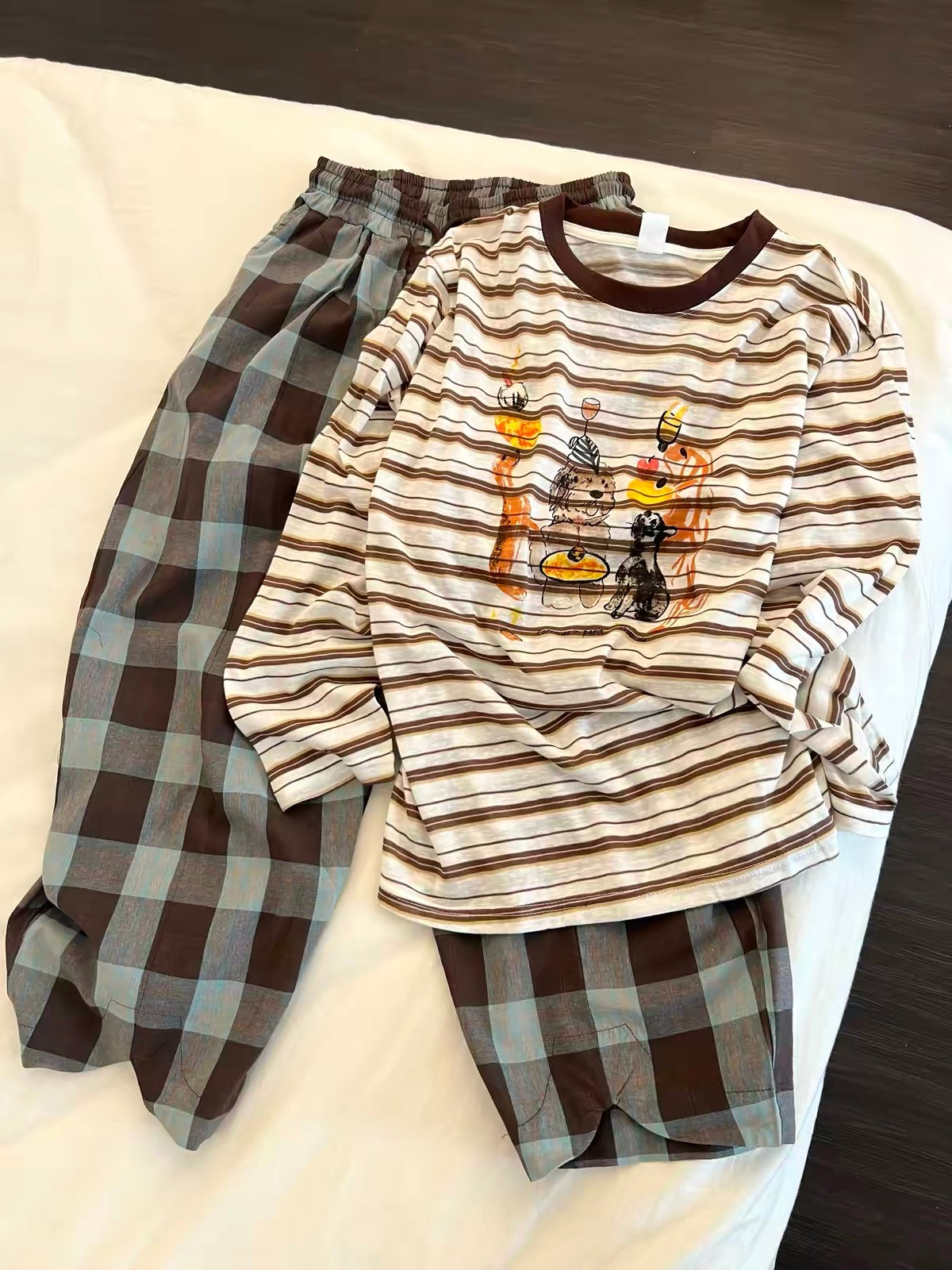 Women's Korean-style loungewear set featuring a striped long-sleeve top with a cartoon print and plaid trousers; a relaxed, laid-back autumn style suitable for wearing both at home and outdoors.