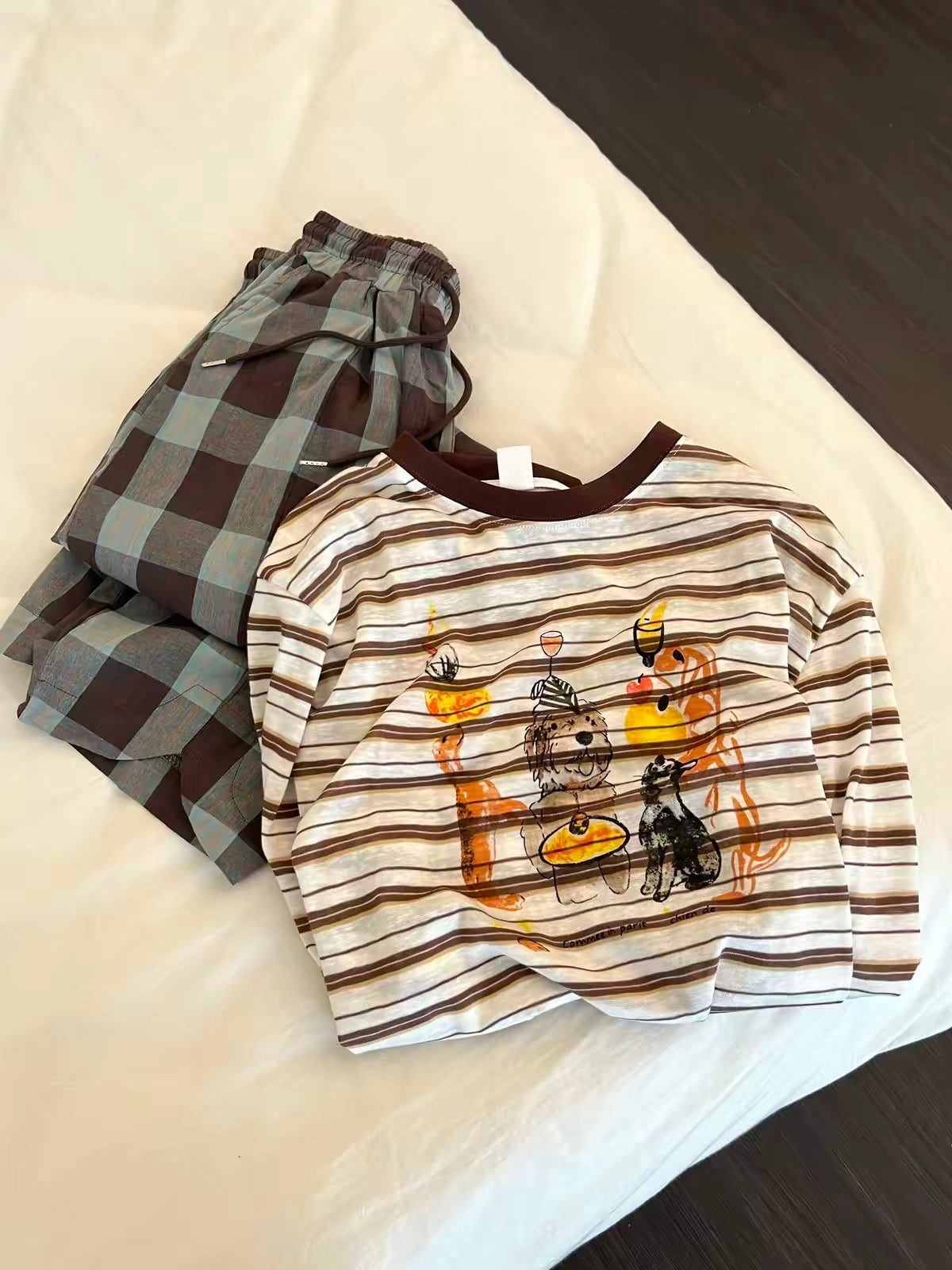 Women's Korean-style loungewear set featuring a striped long-sleeve top with a cartoon print and plaid trousers; a relaxed, laid-back autumn style suitable for wearing both at home and outdoors.