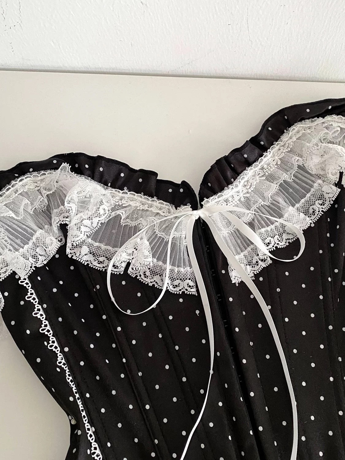 French-style court-inspired top for women, featuring lace trim, sleeveless strapless design, and a fitted boning polka dot pattern.