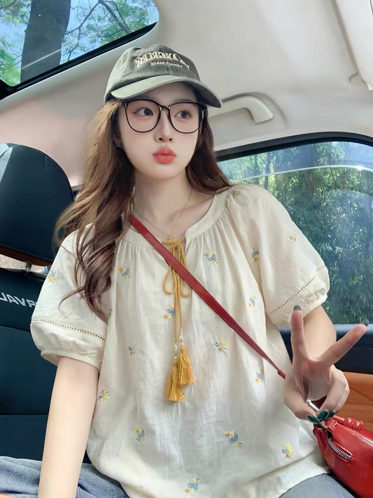 Apricot-colored short-sleeved blouse with puff sleeves and embroidery, perfect for summer 2026. A trendy, youthful, and sun-protective top from a niche brand.