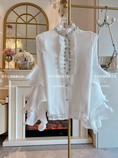 Women's Loose-Fit White Chiffon Shirt (Fall/Winter 2026): Features Elaborate Rhinestone Embellishments, Ruffled Details, Single-Breasted Closure, and Flared Sleeves.
