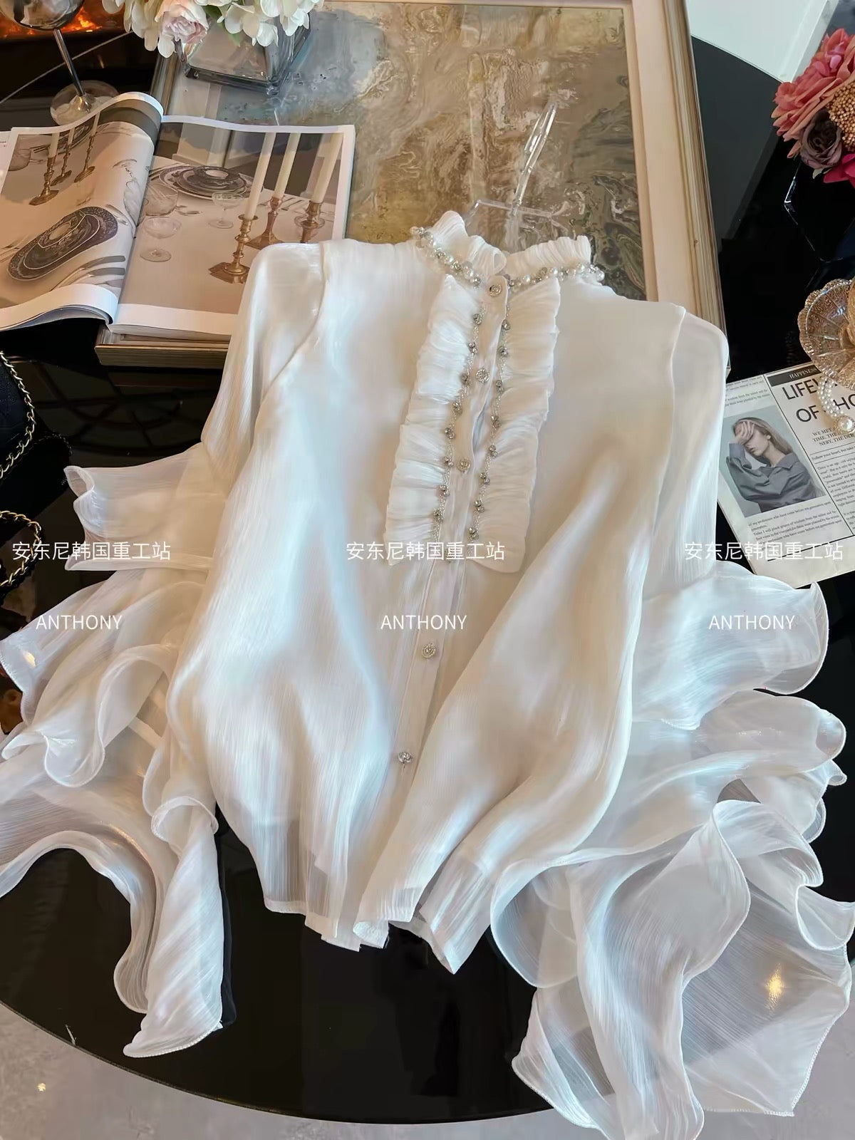 Women's Loose-Fit White Chiffon Shirt (Fall/Winter 2026): Features Elaborate Rhinestone Embellishments, Ruffled Details, Single-Breasted Closure, and Flared Sleeves.