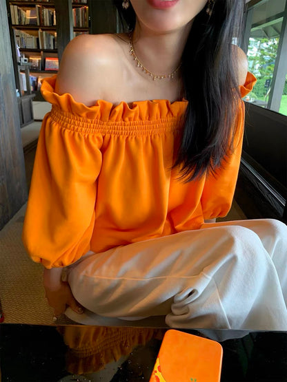 Unique, loose-fitting, off-shoulder top in orange—a stylish, niche design with three-quarter sleeves, perfect for petite frames (New Spring/Summer 2026 Collection).