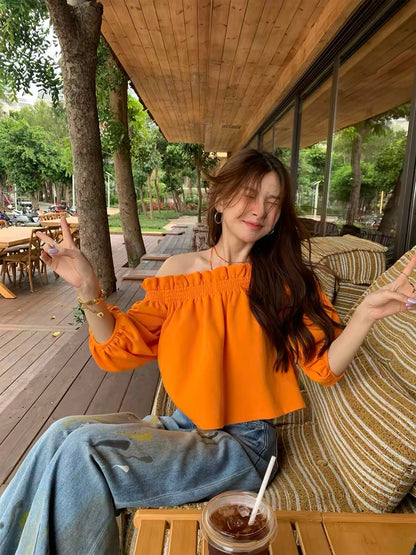 Unique, loose-fitting, off-shoulder top in orange—a stylish, niche design with three-quarter sleeves, perfect for petite frames (New Spring/Summer 2026 Collection).