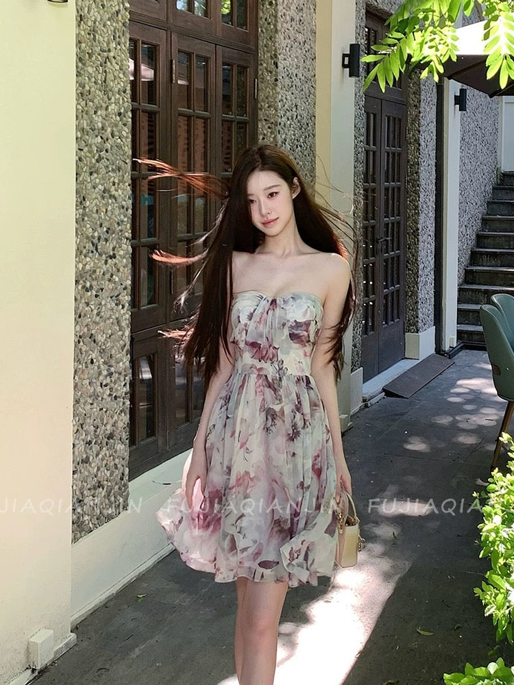 A stunning, French-style romantic dress featuring a dreamy blended print, a sleeveless strapless bodice, and a waist-cinching, slimming fit—perfect for a chic vacation look and highly photogenic.