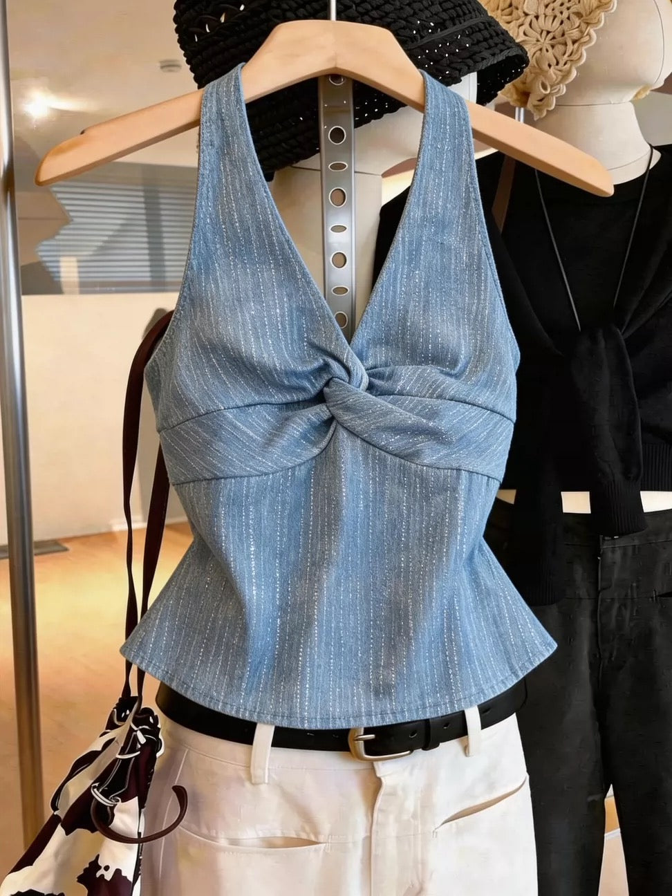 Sexy, sweet, and spicy style: a sleeveless halter-neck top featuring a twisted-front design and a flattering, slim-fit silhouette—a chic, high-fashion take on the denim-look V-neck top.