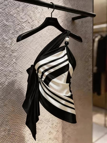 Chic, high-end, and stylish: a youthful black-and-white striped top featuring an asymmetrical design and distinctive camisole detailing—perfect for summer.