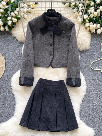 Elegant and sophisticated women's autumn/winter outfit: Short-sleeved long-sleeved jacket with a bow collar paired with a high-waisted pleated skirt.