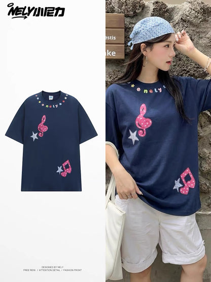 Unisex loose-fit short-sleeve T-shirt featuring a musical note and star appliqué; a versatile, casual crew-neck top with a unique, distinctive design.