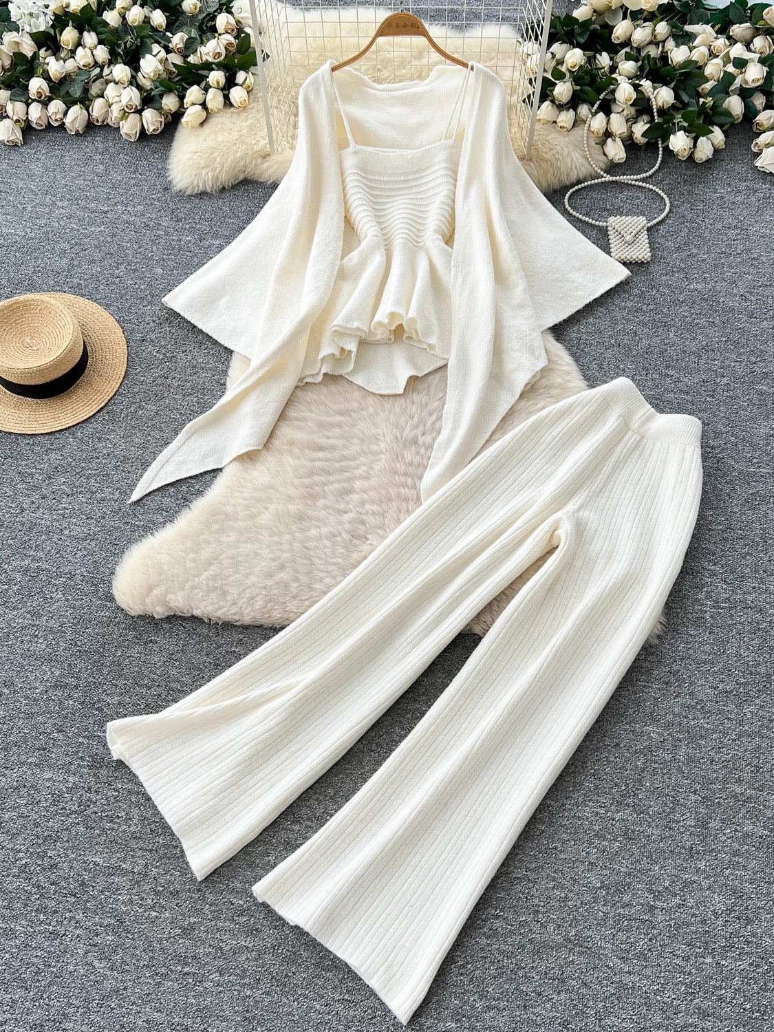 Gentle outfit for women: a three-piece suit with a waist-hugging camisole, a loose sweater, and high-waisted wide-leg pants.