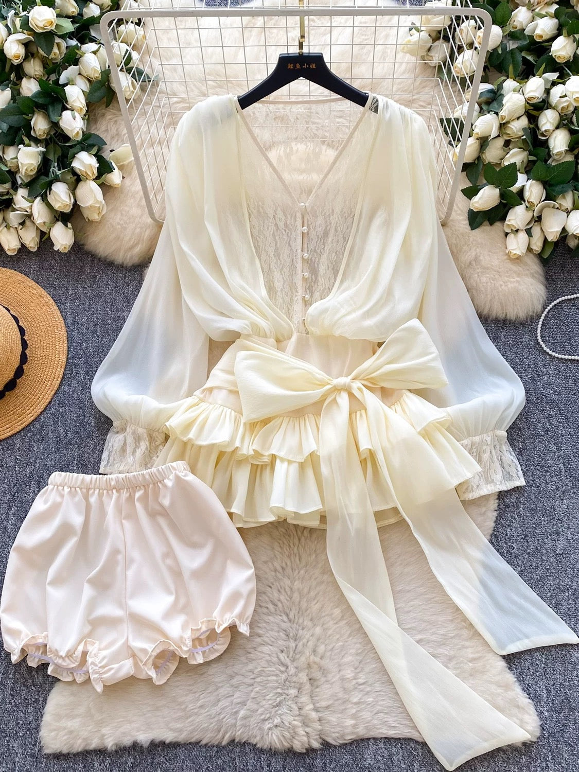A fairy-tale style, unique design featuring a bow tie, cinched waist, lace trim, long sleeves, ruffles, and mesh. Shorts are also available.
